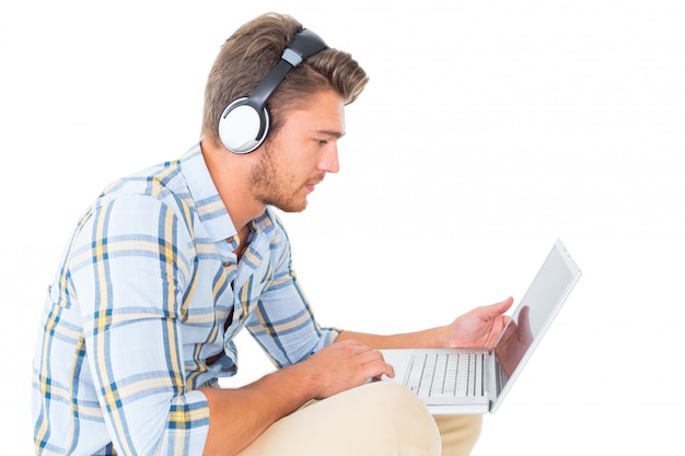 Hombre joven hermoso que se sienta usando la computadora portátil