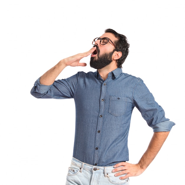 Hombre joven inconformista bostezando sobre fondo blanco