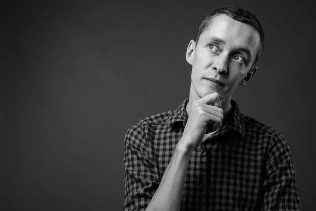 Hombre joven inconformista contra la pared gris en blanco y negro