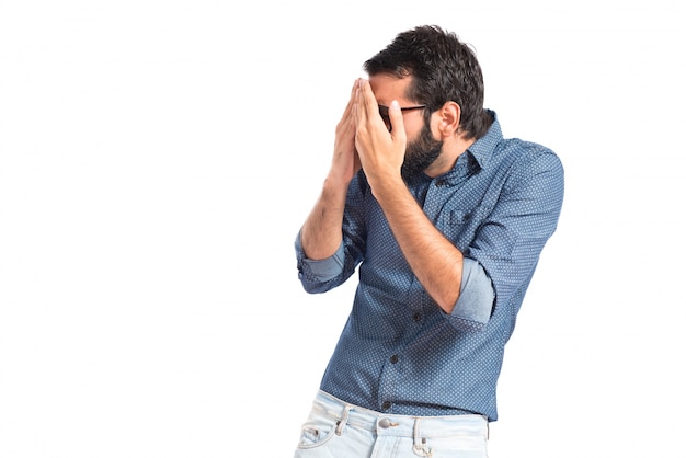 Hombre joven inconformista que cubre sus ojos