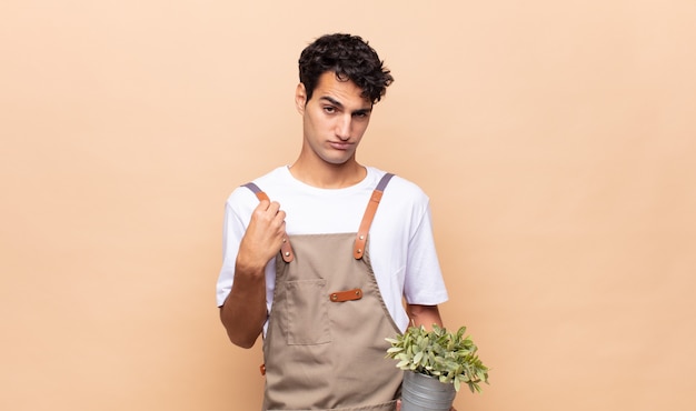 Hombre joven jardinero que parece arrogante, exitoso, positivo y orgulloso, apuntando a sí mismo