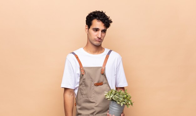 Hombre joven jardinero que se siente triste, molesto o enojado y mirando hacia un lado con una actitud negativa, frunciendo el ceño en desacuerdo