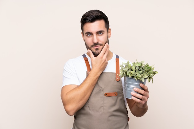 Hombre joven jardinero sobre pared aislada