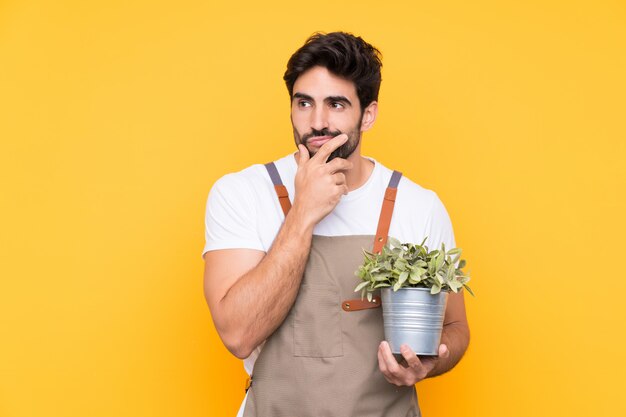 Hombre joven jardinero sobre pared aislada