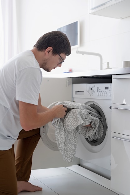 Foto hombre joven con lavadora en el día de lavandería en casa