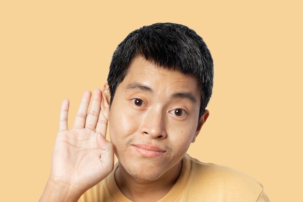 Hombre joven con la mano sobre la oreja escuchando y escuchando rumores o chismes. concepto secreto