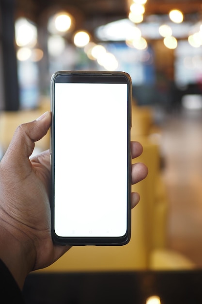 Hombre joven con la mano usando un teléfono inteligente con pantalla verde en una cafetería