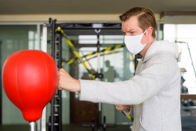 Hombre joven con máscara y boxeo en el gimnasio