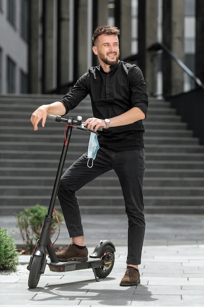 Hombre joven con máscara médica en scooter eléctrico