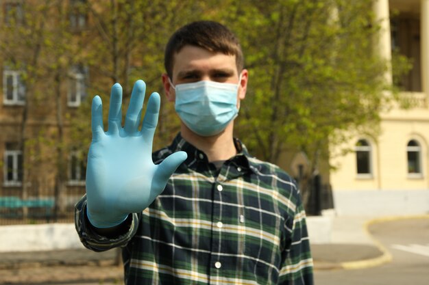 Hombre joven con una máscara protectora y guantes en el parque