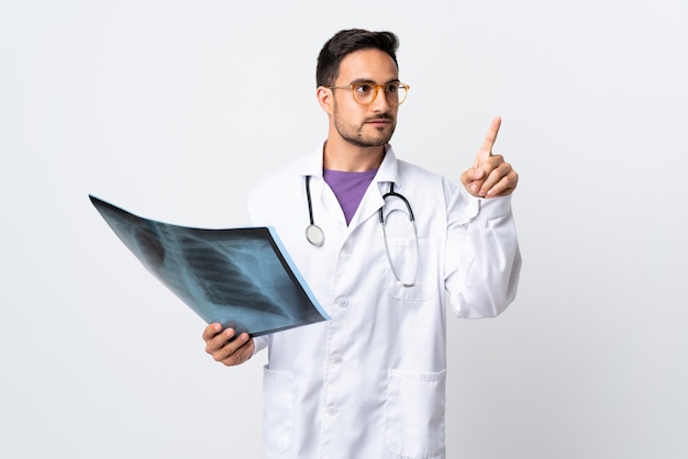 Hombre joven médico sosteniendo una radiografía aislada en blanco tocando en pantalla transparente