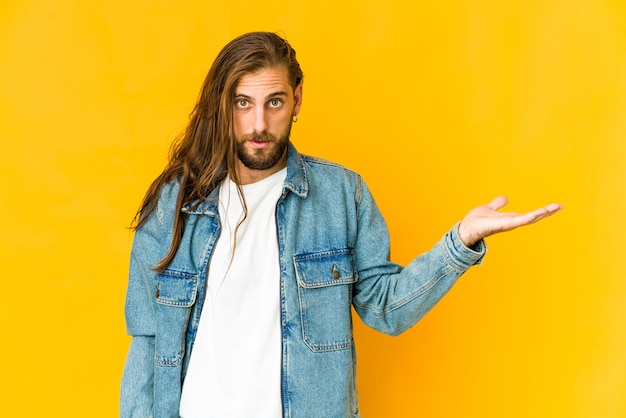 Hombre joven con mirada de pelo largo mostrando algo