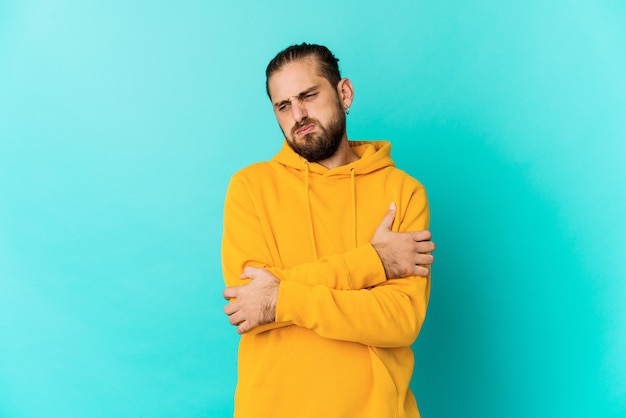 Hombre joven con mirada de pelo largo sopla mejillas, tiene expresión cansada. Concepto de expresión facial.