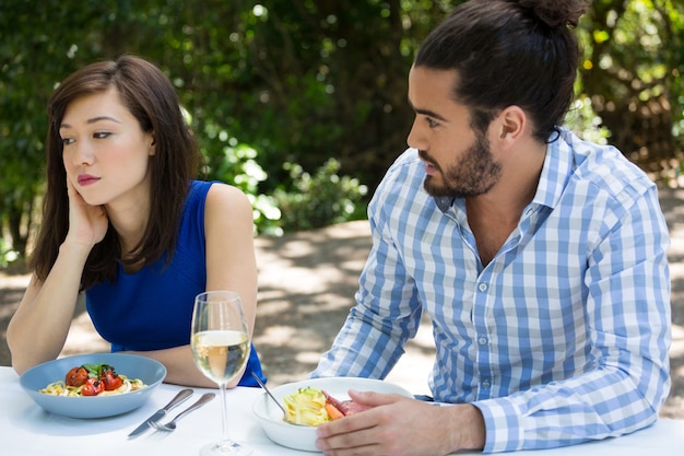 Hombre joven mirando a la mujer molesta en el restaurante al aire libre