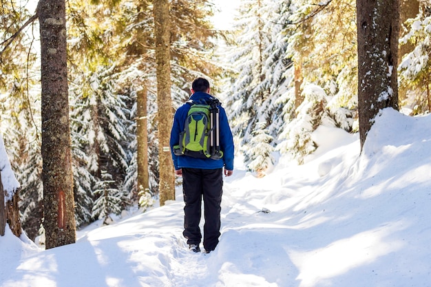 Hombre joven con mochila de senderismo en el bosque de invierno