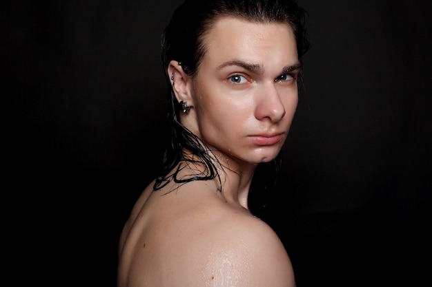 Hombre joven mojado con cabello negro sobre fondo negro