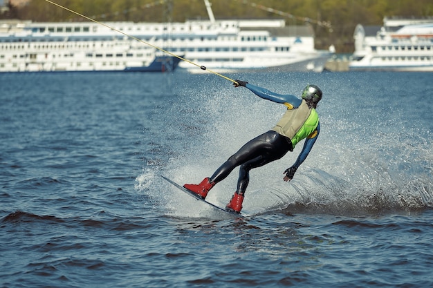 Hombre joven montando wakeboard en un lago de verano