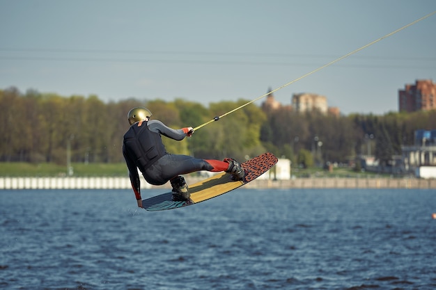 Hombre joven montando wakeboard en un lago de verano.