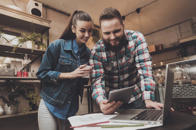 El hombre joven y la mujer están mirando en la tableta.