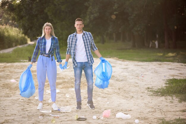 Hombre joven y mujer recogiendo basura al aire libre.