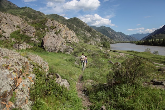 El hombre joven y la mujer van por la carretera de montaña.