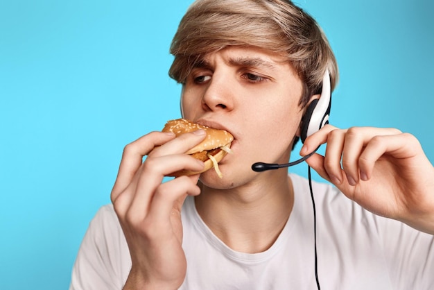 Hombre joven muy hambriento que sostiene la hamburguesa sabrosa