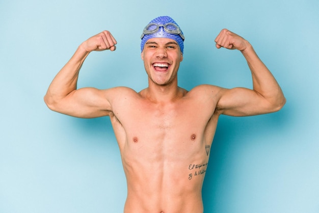 Hombre joven nadador caucásico aislado sobre fondo azul.