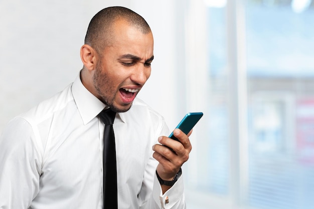 Hombre joven y negro gritando al celular.