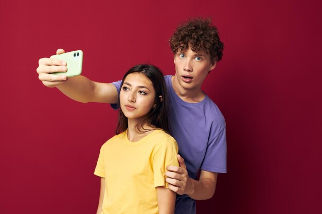 Hombre joven y niña estilo moderno emociones divertido teléfono fondo rojo