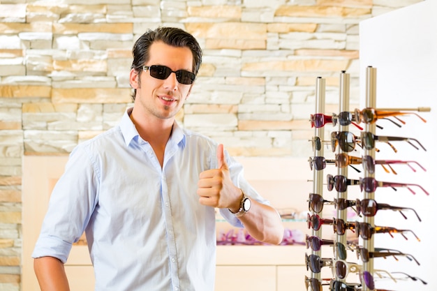 Hombre joven en óptica comprar gafas de sol
