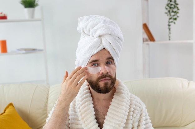 Hombre joven con parches debajo de los ojos en casa concepto de cosmetología para hombres spa en casa cuerpo y