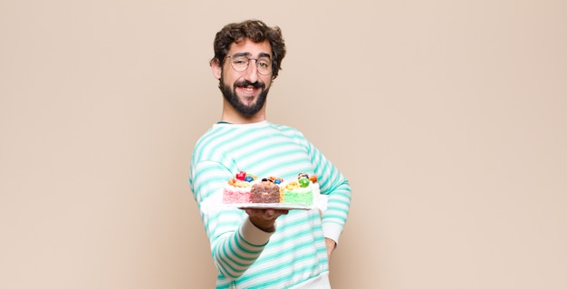 Hombre joven con un pastel contra la pared plana