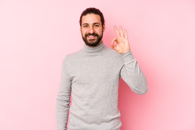 Hombre joven de pelo largo aislado en un gesto de ok mostrando alegre y seguro rosa.