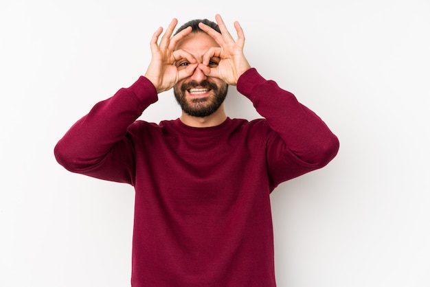 Foto hombre joven de pelo largo aislado en una pared blanca que muestra signo bien sobre los ojos