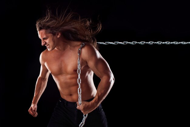 Hombre joven con el pelo largo arrastrando algo detrás de él.