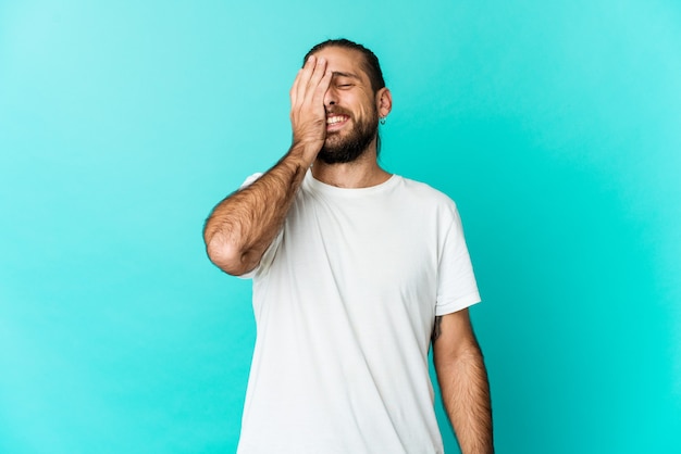 El hombre joven con el pelo largo mira riendo emoción feliz, despreocupada, natural.