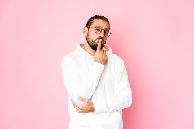 El hombre joven con el pelo largo parece infeliz mirando a puerta cerrada con expresión sarcástica.