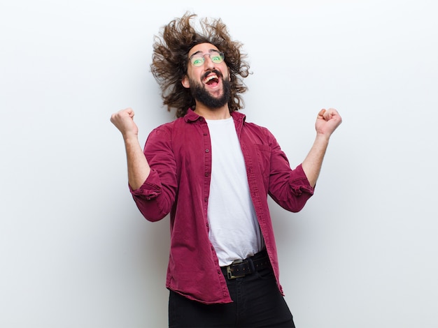 Hombre joven con el pelo loco en movimiento bailando y celebrando