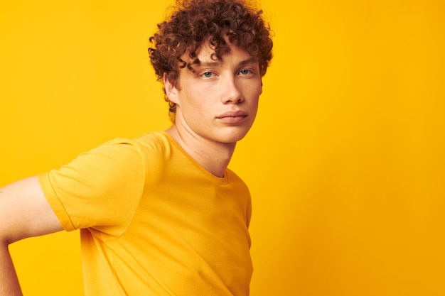 Hombre joven de pelo rizado con gafas elegantes camiseta amarilla posando disparo monocromático