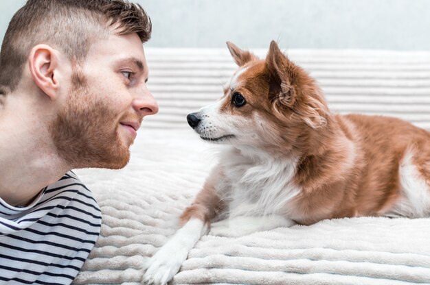 Hombre joven y un perro se miran. Amigos del concepto