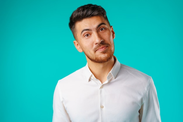 Hombre joven positivo en camisa casual blanca de pie con sonrisa feliz