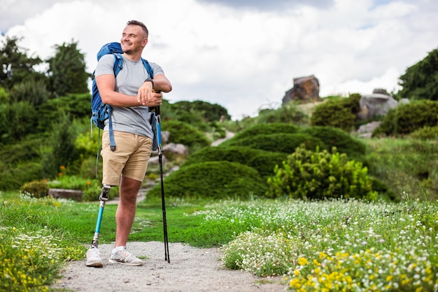 Hombre joven positivo con prótesis de pie al aire libre mientras disfruta del turismo