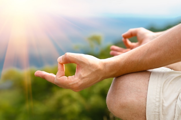 Foto hombre joven en postura de loto. hombre practicando yoga al aire libre