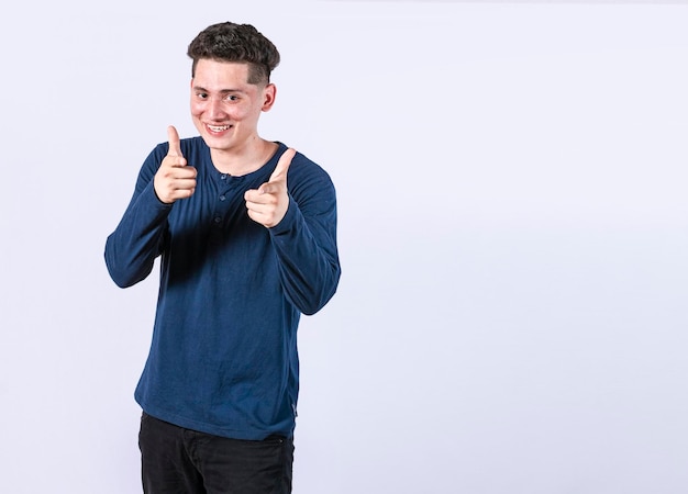 Hombre joven con los pulgares hacia arriba sobre fondo blanco chico positivo con los pulgares hacia arriba haciendo bien Hombre sonriente mostrando gesto bien mirando a la cámara