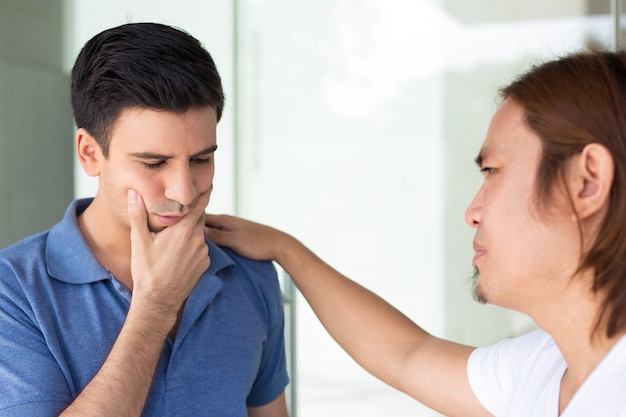 Hombre joven que apoya al amigo deprimido al aire libre