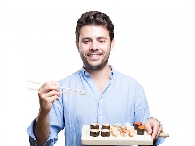 Hombre joven que come sushi en el fondo blanco