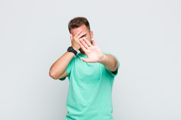 Hombre joven que cubre la cara con la mano