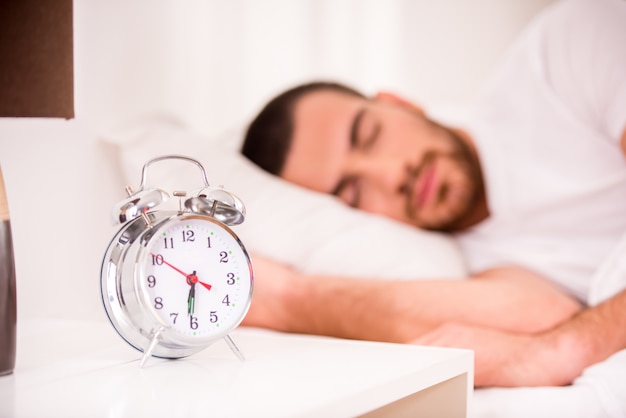 Hombre joven que duerme en cama cómoda en casa.