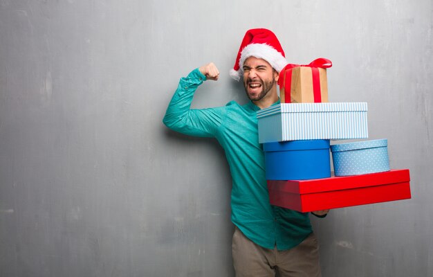 Hombre joven que lleva un sombrero de santa con regalos que no se rinde