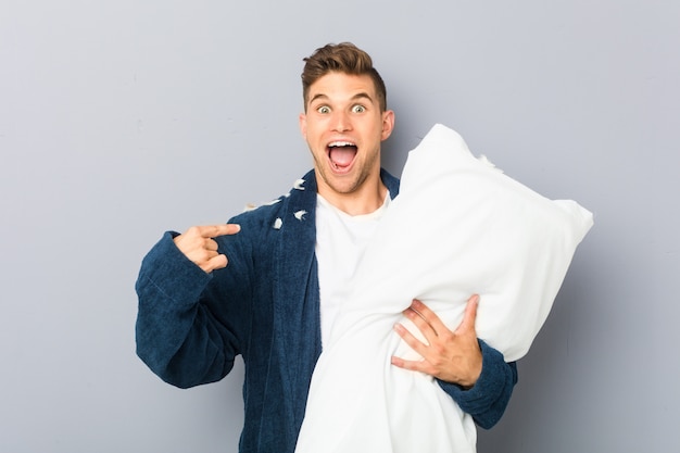 El hombre joven que llevaba pijama sosteniendo una almohada sorprendió apuntándose a sí mismo, sonriendo ampliamente.